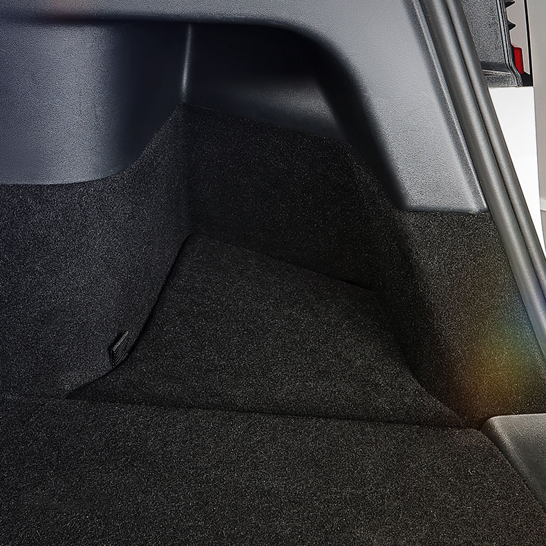 Interior of a car's trunk/cargo area with dark carpeted floor and side panel trim