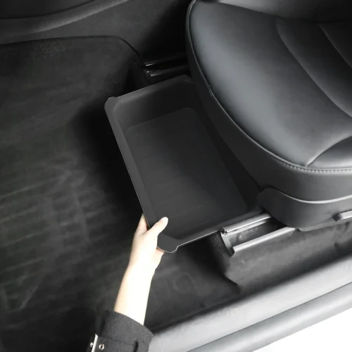 Hand reaches for and slides out a small black plastic storage tray from under a car seat in the vehicle interior Simplified version