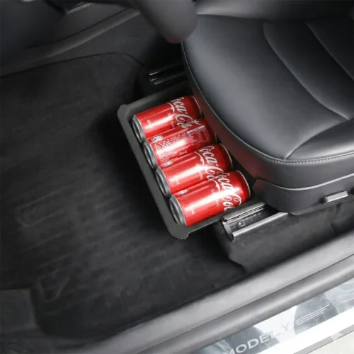 Four Coca‑Cola cans sit in a pull‑out cup holder under a car seat.