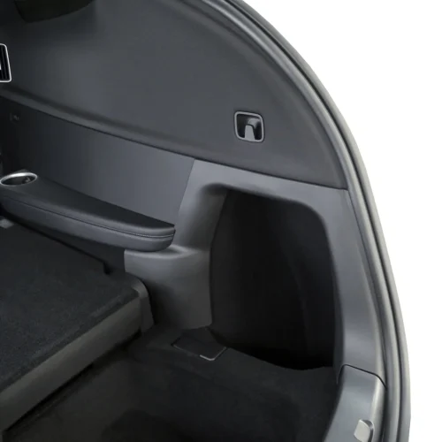 Interior of a car trunk side panel with a small rectangular latch, a folded rear seat, and a cup holder.