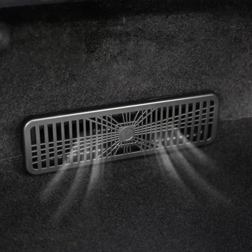 Rectangular vent grille with a circular central hub behind it, mounted in a dark carpeted surface (car interior)., close-up of a vent with a radial grille inside a black fabric interior, rectangular air vent in a dark trunk area., Vent/grille with a central round hub and radial spokes, located on a dark interior surface, likely a vehicle. , Air vent in a dark interior showing a grid pattern and central hub. , Functional: ventilation grille in a dark car interior.