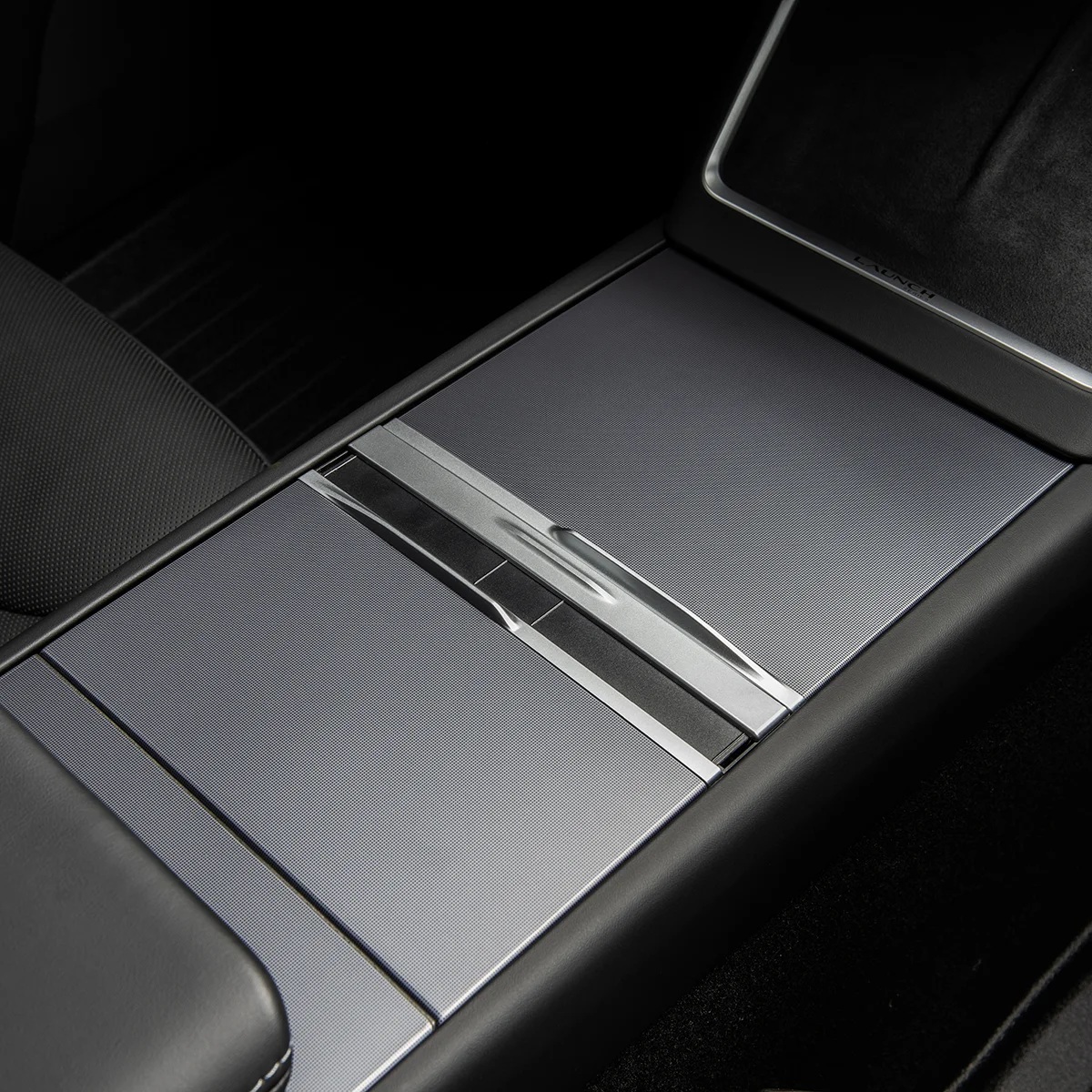Center console of a car with brushed metal panels and a sliding cover, part of a luxury interior