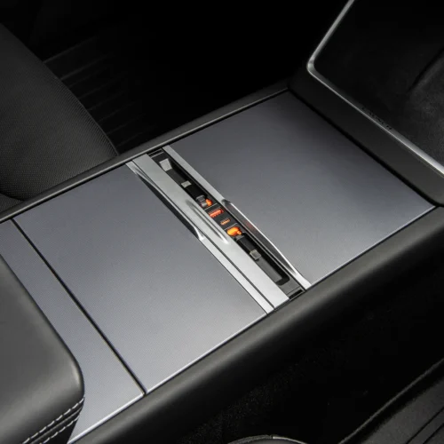 Close-up of a car center console with a metal sliding cover and orange-lit seat heater indicators.