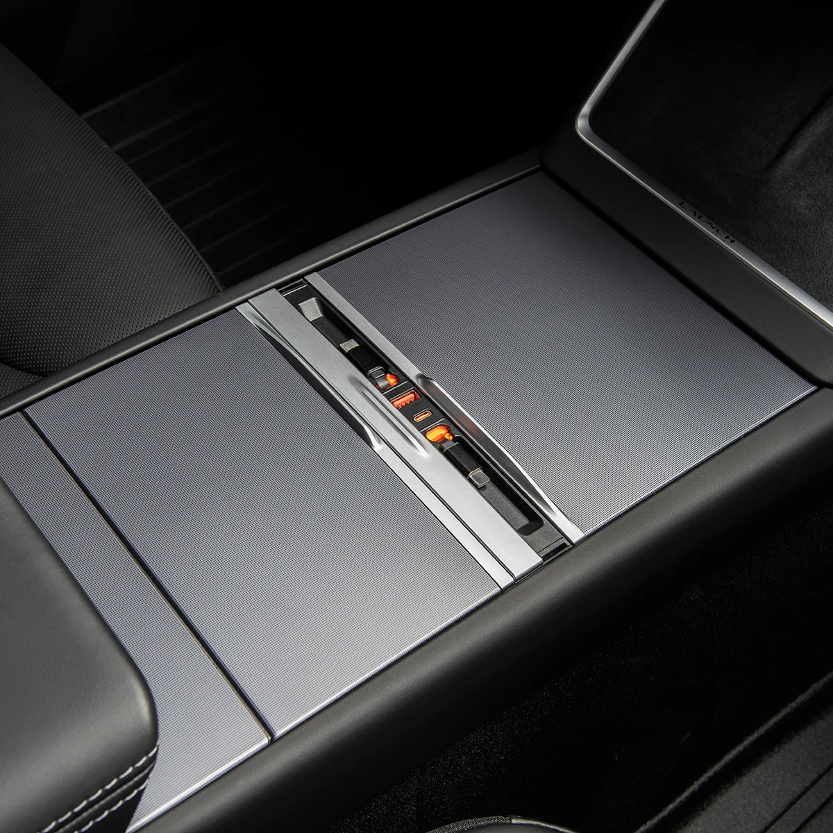 Close-up of a car center console with a metal sliding cover and orange-lit seat heater indicators.