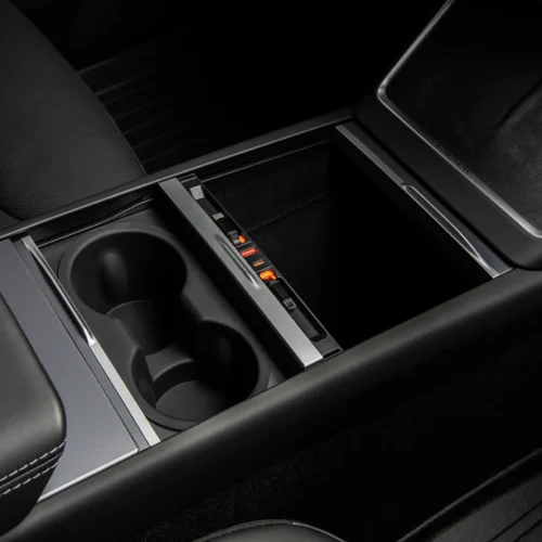 Car center console with two cup holders and a sliding storage tray with orange indicator lights.