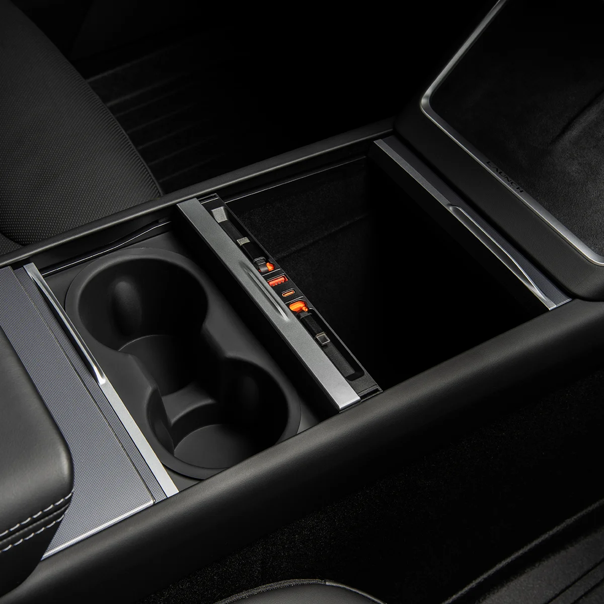 Car center console with two cup holders and a sliding storage tray with orange indicator lights.