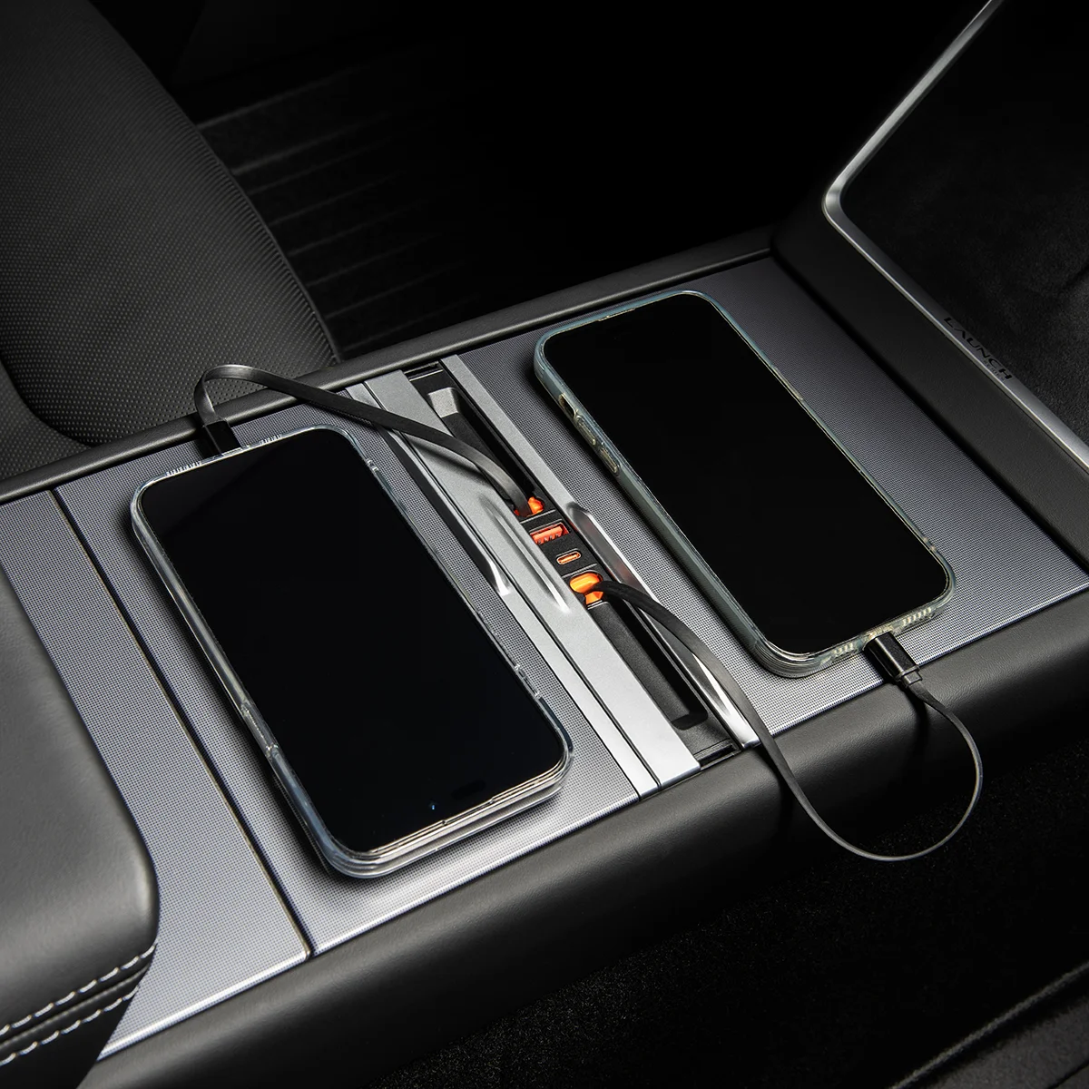 Two smartphones resting in a car's center console charging dock with cables connected and orange indicator lights showing.