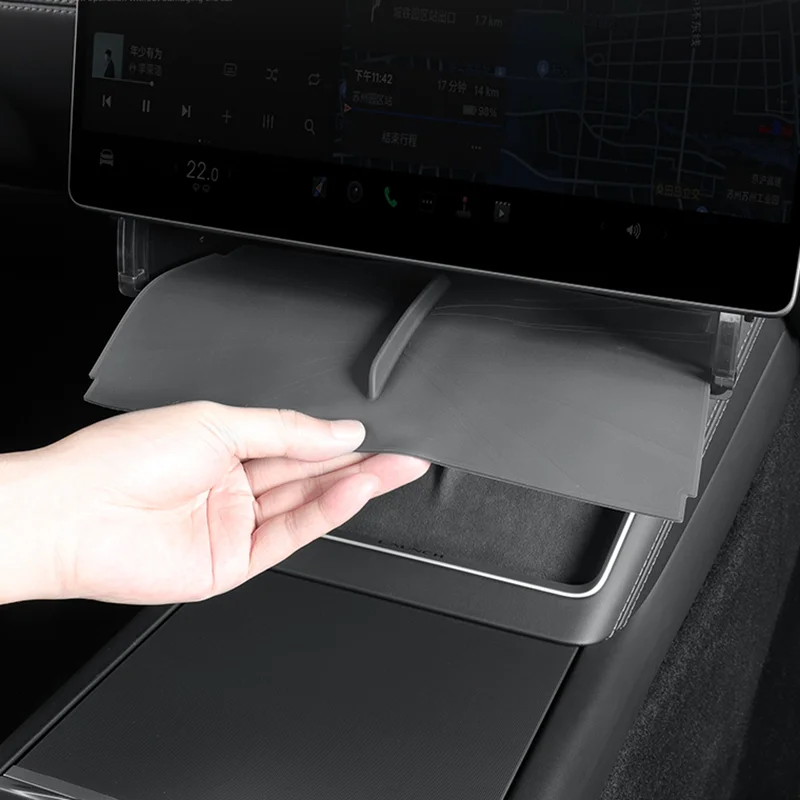 Retractable tray being pulled out from under the car's touchscreen center console by a hand.