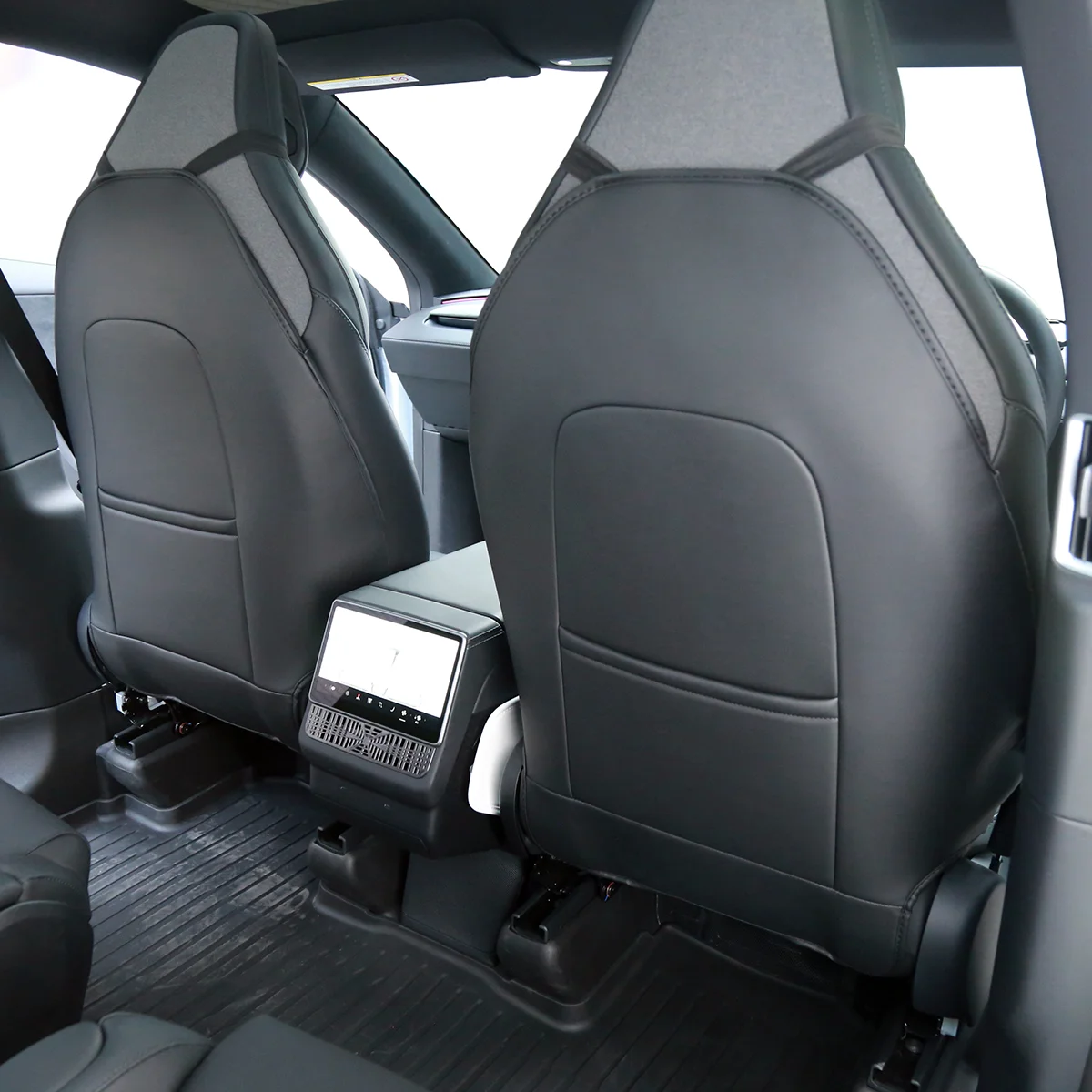 View of the car rear cabin with black leather seats and a touchscreen climate control panel mounted between the front seats+.