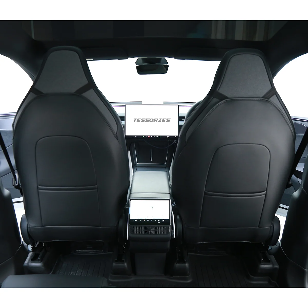 View from the rear seats of a modern car interior with two black leather seats and a central touchscreen displaying 'TESSORIES'.