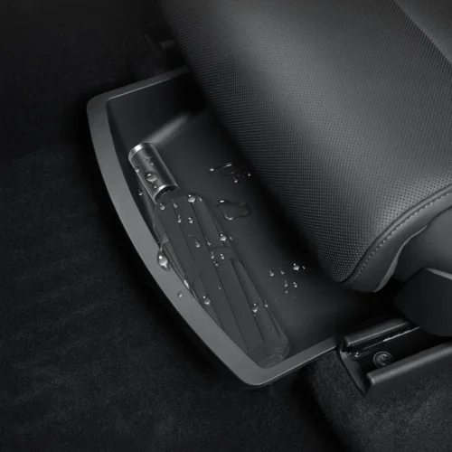 Folded seat belt stored in a car's seat-track tray beneath the perforated seat, with water droplets on the surface.