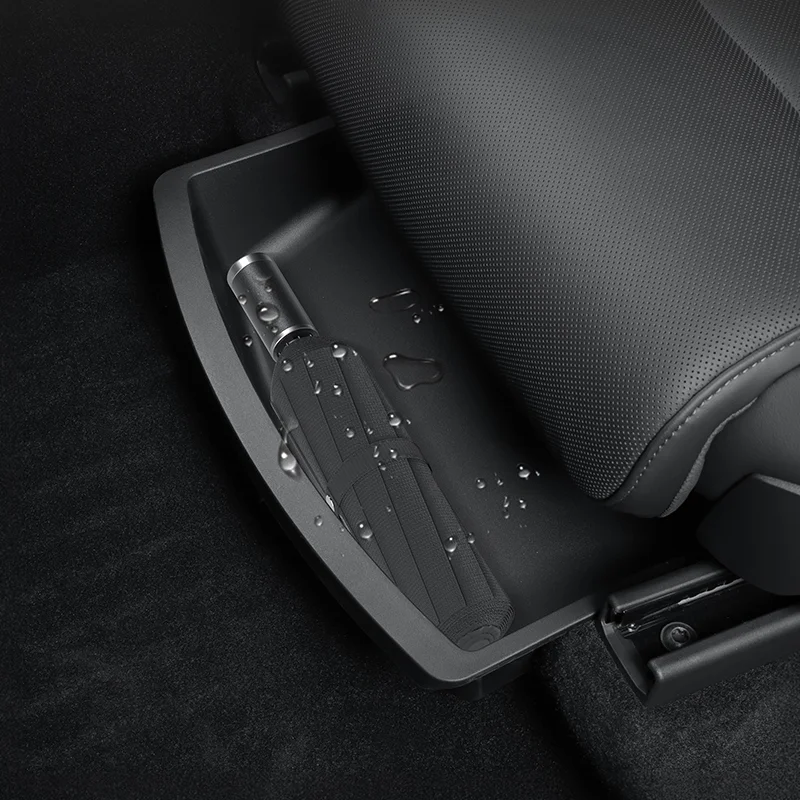 Folded seat belt stored in a car's seat-track tray beneath the perforated seat, with water droplets on the surface.