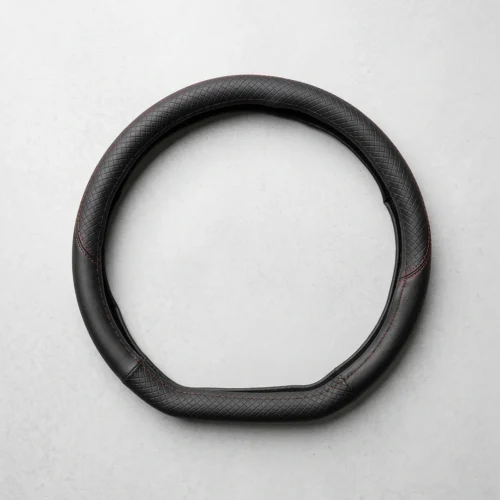 Black textured leather steering wheel cover with red stitching, laid flat as a circular ring on a light gray surface.