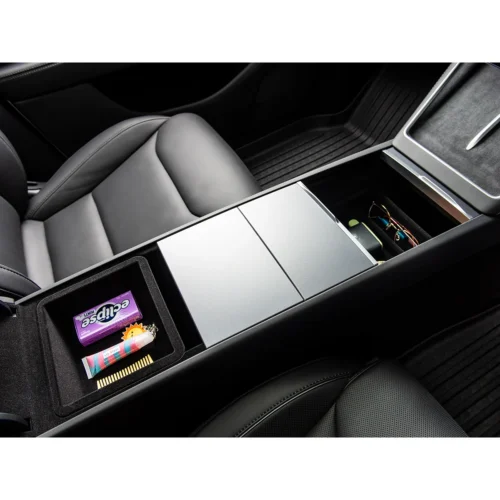 Inside a car's center console, an open storage tray holds a snack bar and small items beside the seat panel.