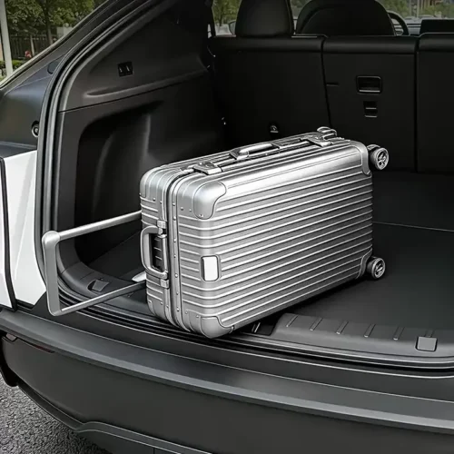 Silver hard-shell suitcase in the SUV cargo area, resting on a built-in luggage rail with rear seats upright.