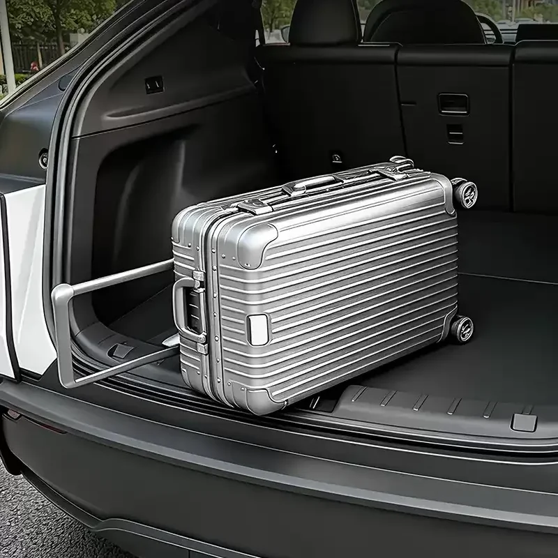 Silver hard-shell suitcase in the SUV cargo area, resting on a built-in luggage rail with rear seats upright.