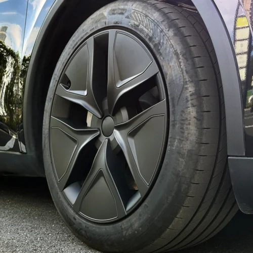 Close-up of a dark gray alloy wheel and tire on a car, showing an intricate spoke design and low-profile tire