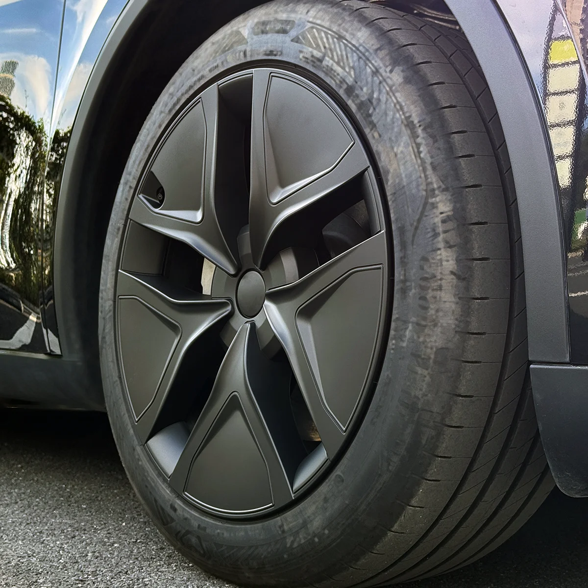Close-up of a dark gray alloy wheel and tire on a car, showing an intricate spoke design and low-profile tire