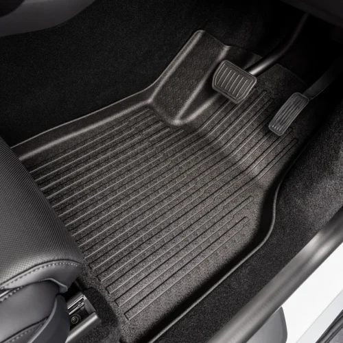 Driver's-side car floor with a black ribbed rubber mat and two pedals (accelerator and brake) visible at the top-right of the image.
