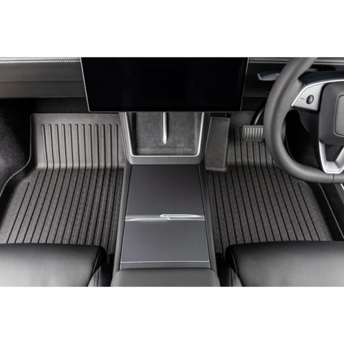 Interior view of a car cockpit highlighting the center console, large screens, steering wheel, and ribbed floor mats in a dark, modern cabin