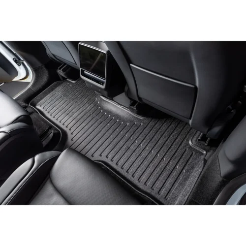 Backseat area of a car with a ribbed rubber floor mat and a small center display between the front seats.