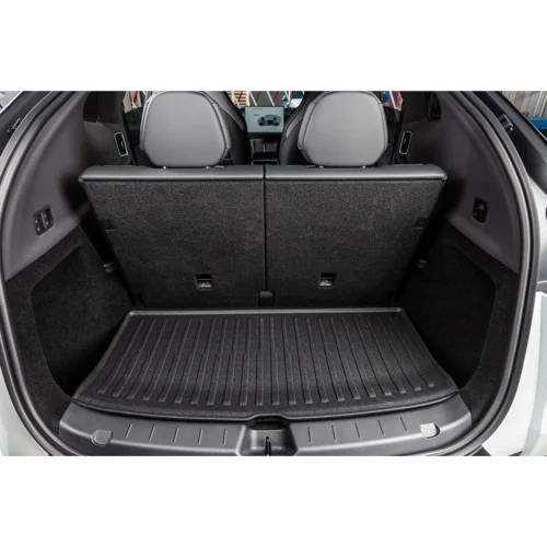 Spacious car trunk with rear seats upright and a textured cargo mat in place.