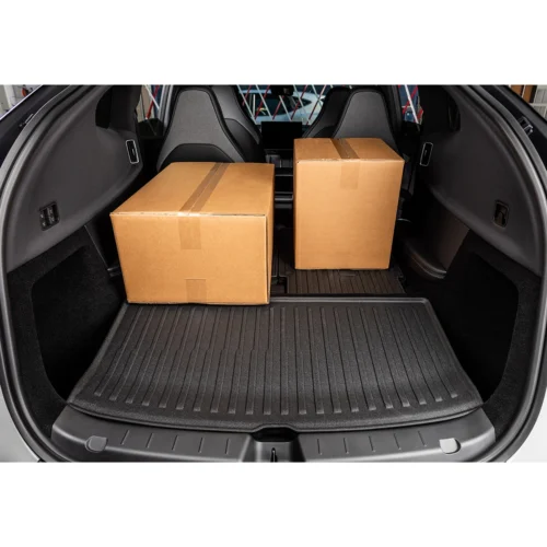 Two cardboard boxes in the trunk of a car on a textured cargo mat in the rear cargo area of the vehicle.