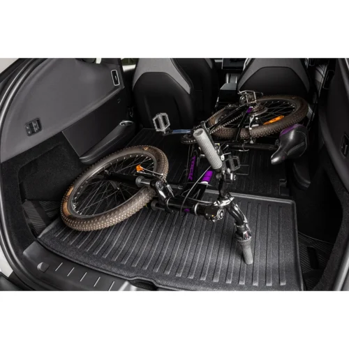 Mountain bike lying in the back cargo area of a car, wheels and pedals visible, ready for transport.
