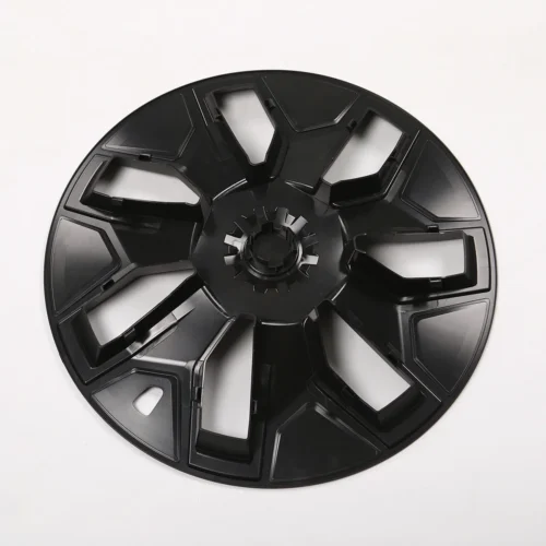 Large black plastic circular component with eight spokes and central gear, placed on a white surface.