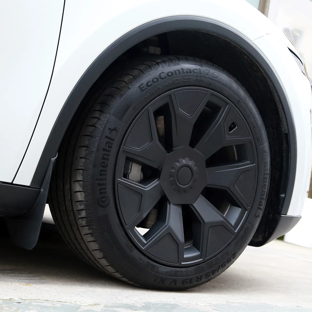 Close-up of a white car's front wheel with a black rim and Continental EcoContact 7S tire.